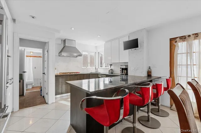 a kitchen with stainless steel appliances granite countertop a dining table chairs and a refrigerator