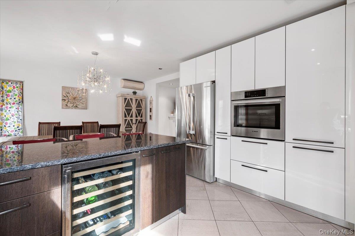 82-06 166th Street Queens, NY 11432 - Photo 6 of 25 Kitchen with modern cabinets, appliances with stainless steel finishes, wine cooler, and dark stone countertops
