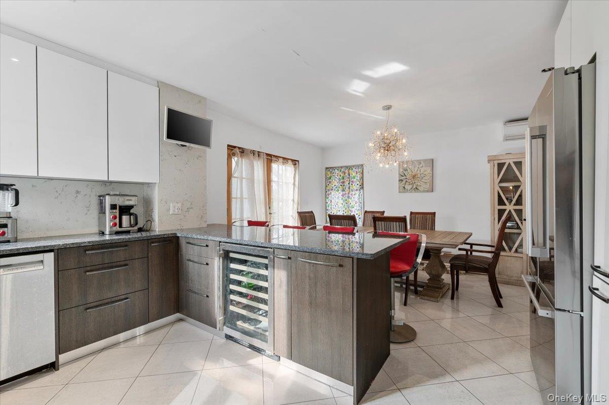 82-06 166th Street Queens, NY 11432 - Photo 8 of 25 Kitchen with white cabinets, a peninsula, dark stone countertops, appliances with stainless steel finishes, and modern cabinets