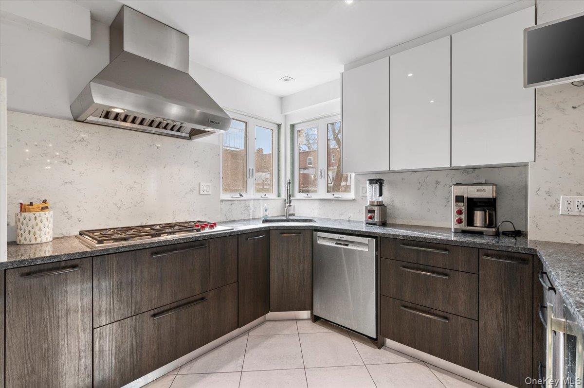 82-06 166th Street Queens, NY 11432 - Photo 9 of 25 Kitchen featuring island exhaust hood, dark brown cabinetry, white cabinets, stainless steel appliances, and dark stone counters