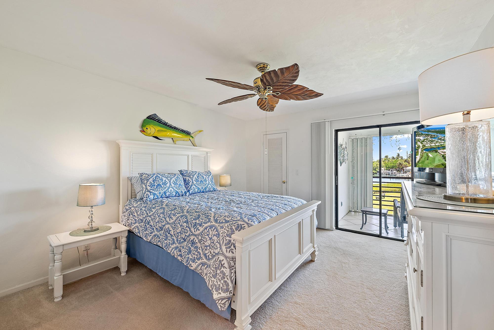 755 Saturn Street, Unit D205 Jupiter, FL 33477 - Photo 16 of 22 a bedroom with a bed and a chandelier