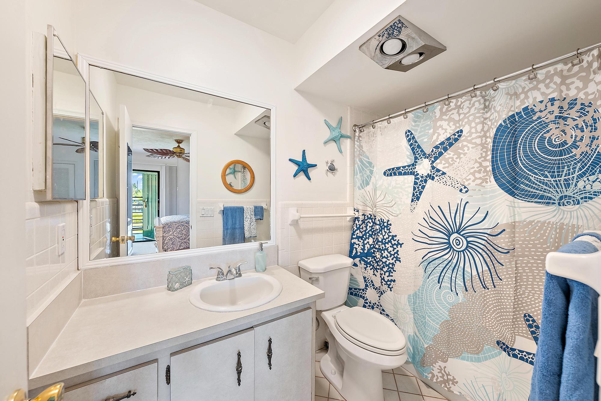 755 Saturn Street, Unit D205 Jupiter, FL 33477 - Photo 18 of 22 a bathroom with a toilet a sink and a mirror