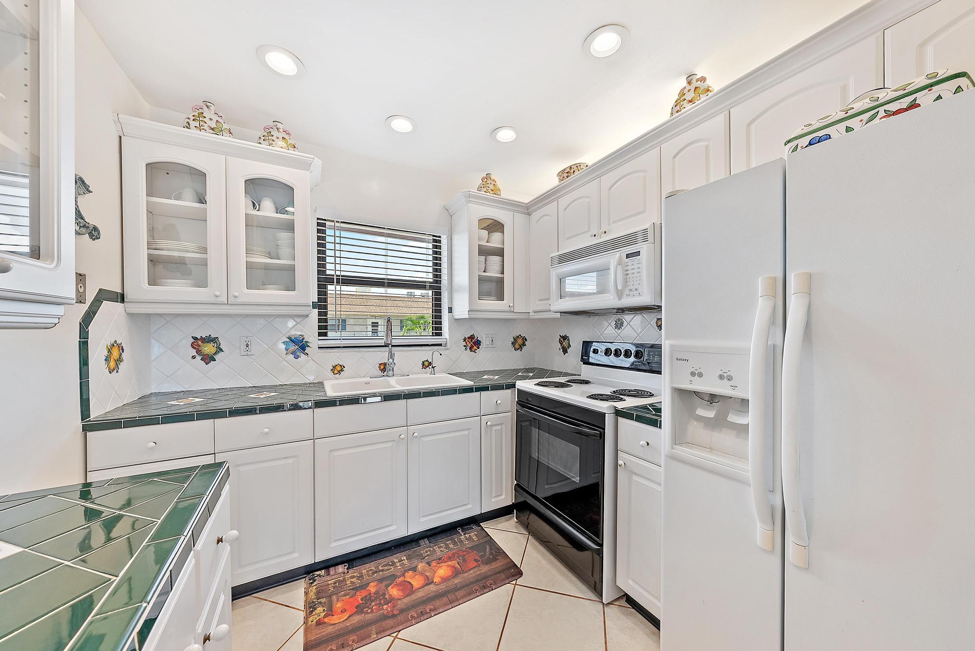 755 Saturn Street, Unit D205 Jupiter, FL 33477 - Photo 7 of 22 a kitchen with white cabinets and white appliances