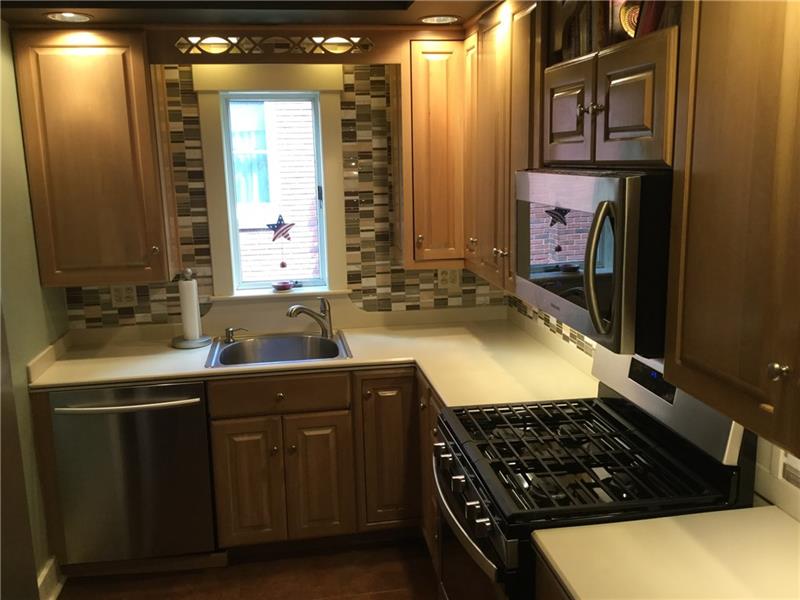THE KITCHEN BOASTS CUSTOM CABINETS, STAINLESS STEEL APPLIANCE AND BACK SPLASH TILE.