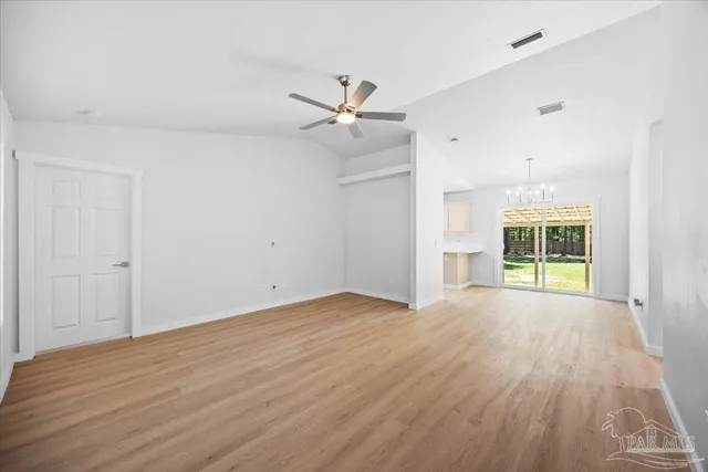 an empty room with wooden floor ceiling fan and windows