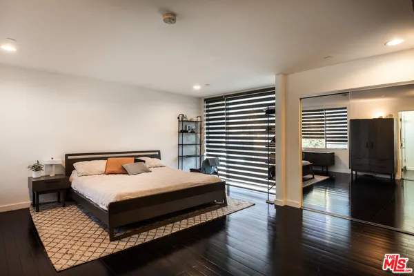 a bedroom with a bed wooden floor and a view of bedroom