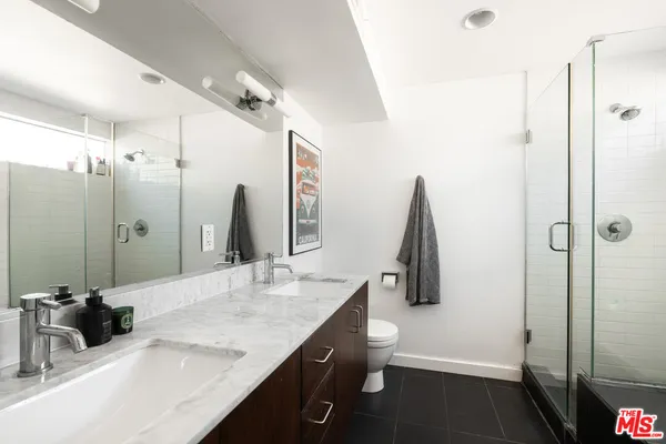 a bathroom with a double vanity sink a toilet and a shower