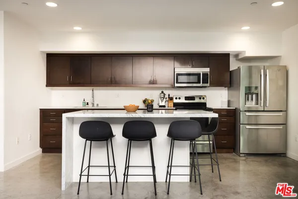 a kitchen with granite countertop a refrigerator and a stove top oven