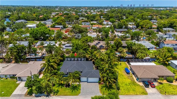 an aerial view of residential houses with outdoor space and trees all around