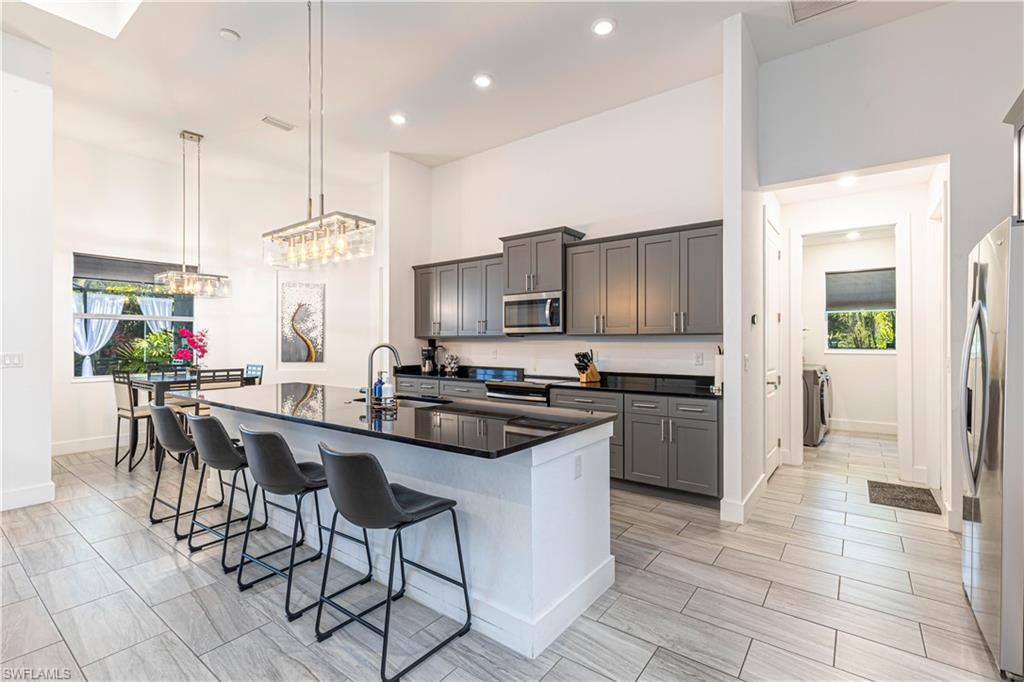 27180 Williams Road Bonita Springs, FL 34135 - Photo 10 of 42 a kitchen with stainless steel appliances granite countertop a stove top oven a sink dishwasher a dining table and chairs