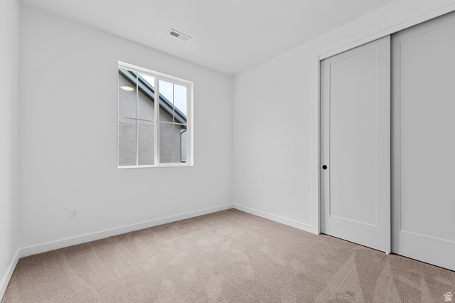 1869 South 2425 West Ogden, UT 84401 - Photo 9 of 22 Unfurnished bedroom featuring light colored carpet and a closet