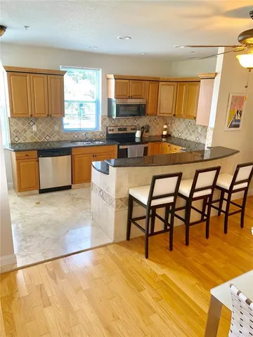 a kitchen with stainless steel appliances kitchen island granite countertop a table chairs and a refrigerator