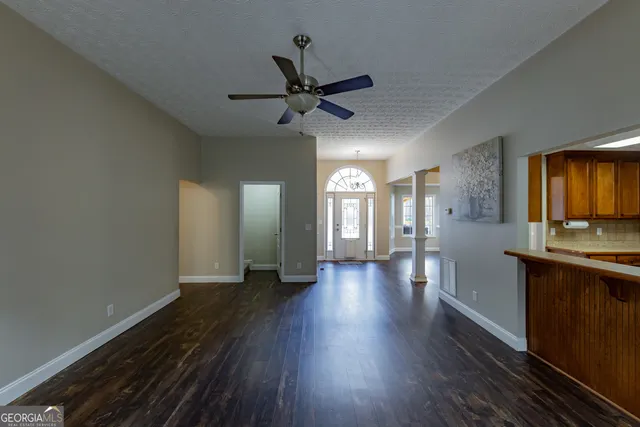 a view of empty room with wooden floor and fan