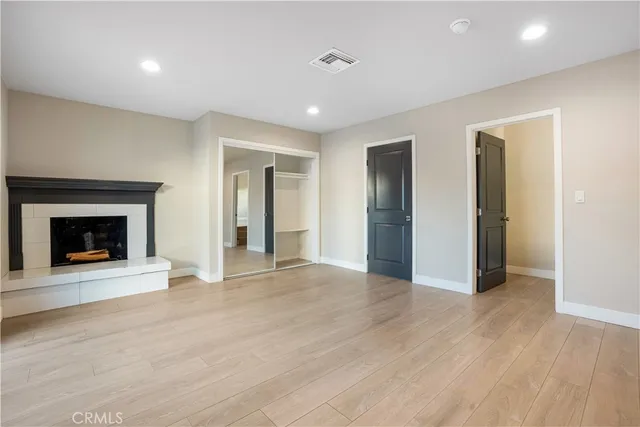 a view of an empty room with wooden floor fireplace and a window