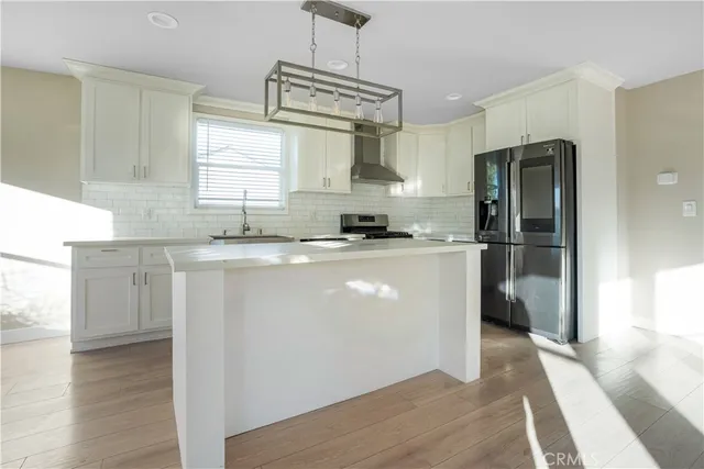 a kitchen with stainless steel appliances granite countertop a refrigerator a sink dishwasher a stove with wooden floor and cabinets