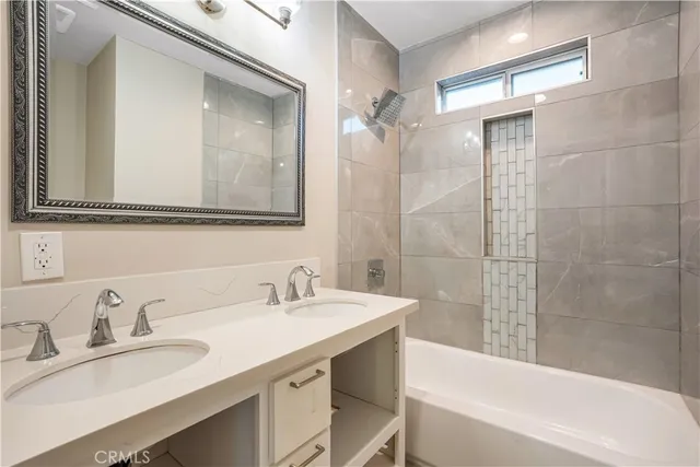 a bathroom with a sink double vanity granite tub shower and a mirror