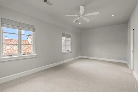 an empty room with chandelier fan and windows