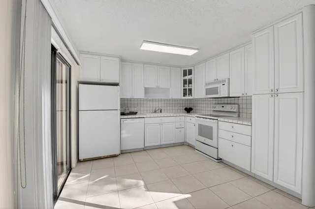 a kitchen with white cabinets and white appliances