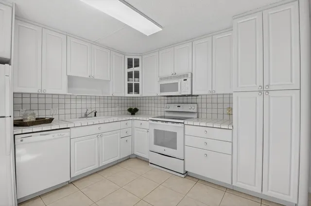 a kitchen with white cabinets and white appliances