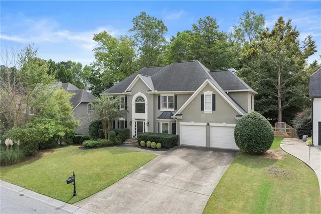 a view of a house with a yard plants and large tree