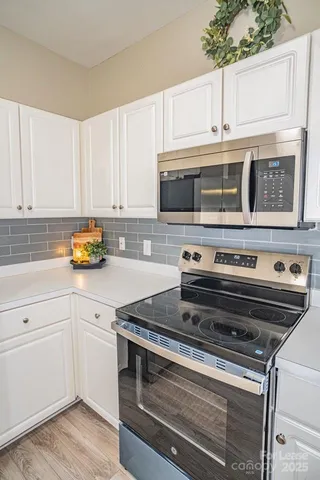 a kitchen with stainless steel appliances granite countertop a stove and white cabinets