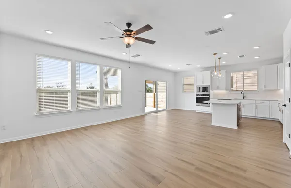 a view of an empty room with kitchen view and a floor to ceiling window
