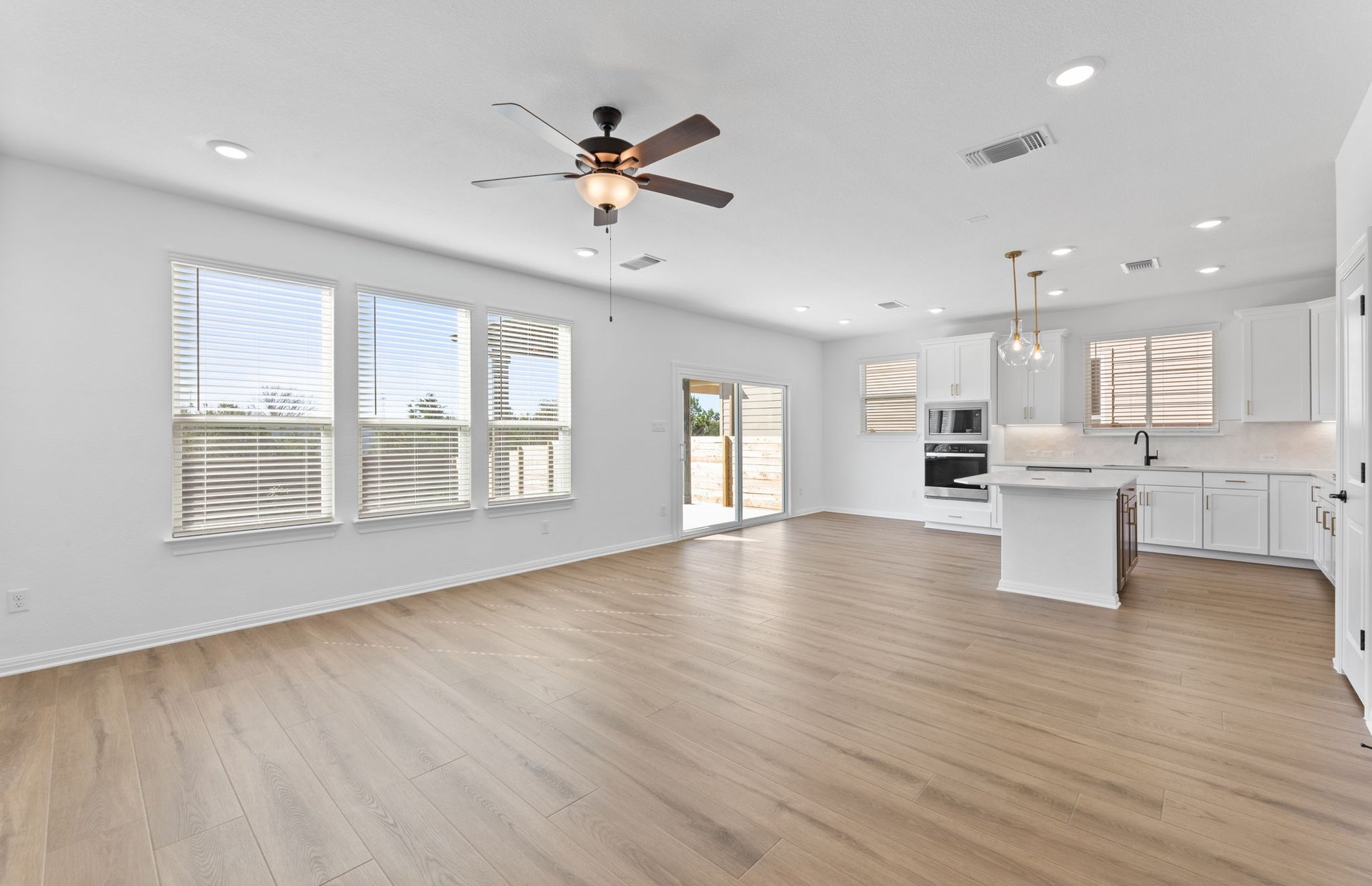 528 Knot Drive Leander, TX 78641 - Photo 7 of 29 a view of an empty room with wooden floor and a kitchen