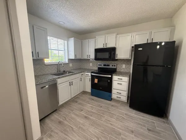 a kitchen with a refrigerator a sink a stove a microwave and cabinets