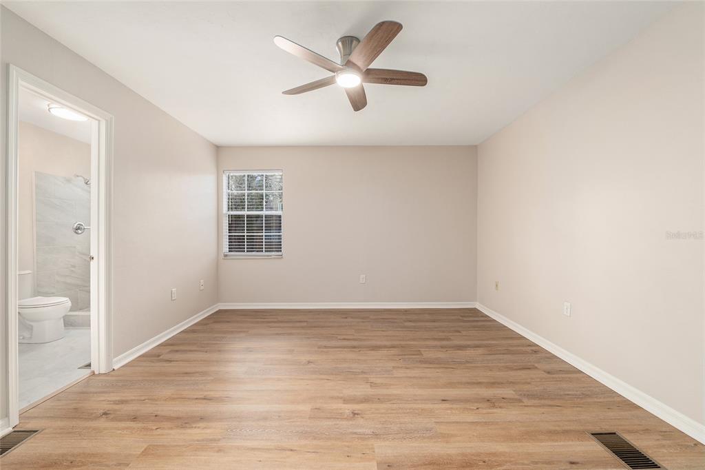 9755 Southwest 52nd Road Gainesville, FL 32608 - Photo 27 of 43 an empty room with wooden floor and a ceiling fan