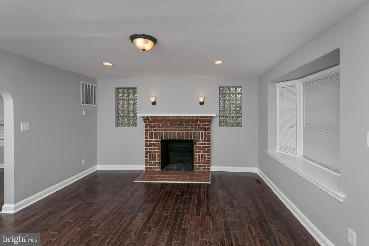 1901 Crestview Road Baltimore, MD 21239 - Photo 4 of 30 a view of an empty room with wooden floor fireplace and a window