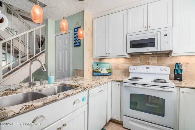a kitchen with granite countertop white cabinets and white appliances