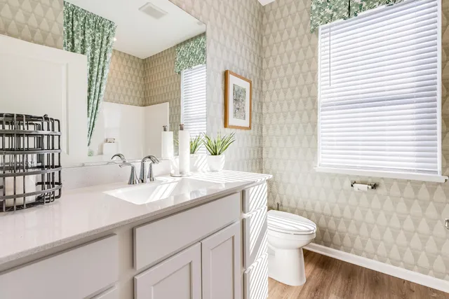 a bathroom with a granite countertop sink toilet and mirror