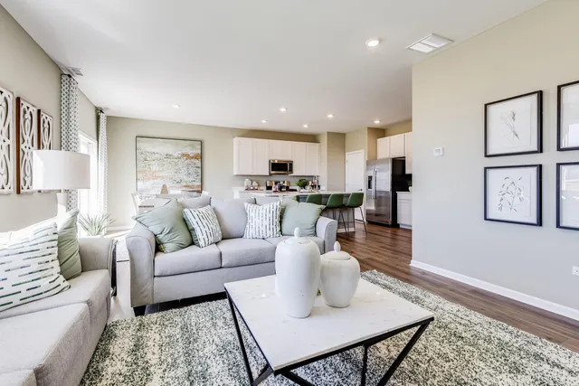 a living room with furniture kitchen view and a wooden floor