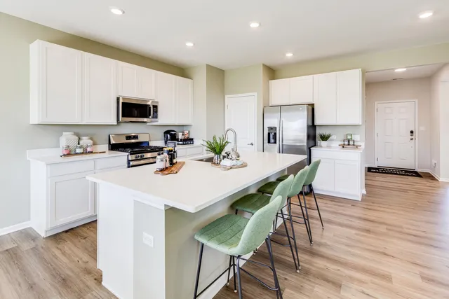 a kitchen with a dining table chairs refrigerator and microwave