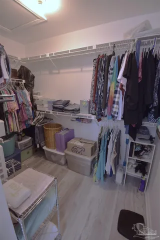 a view of walk in closet with clothes and shoes