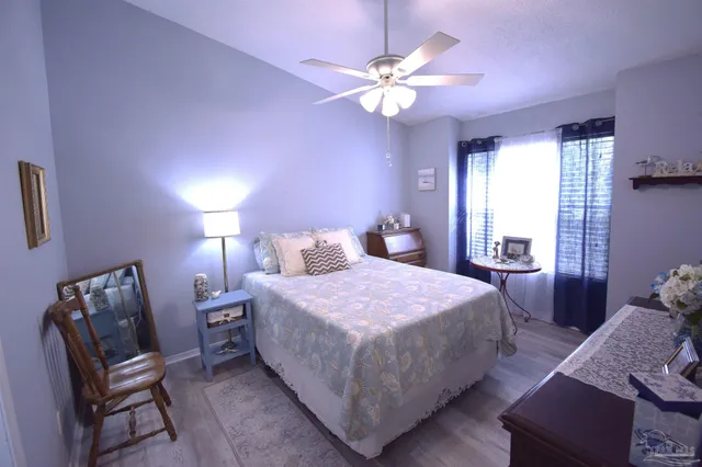 a bedroom with a bed table chair and window