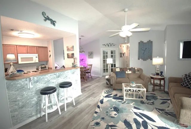 a living room with furniture a chandelier and kitchen view