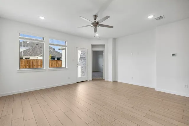 a view of an empty room with a window and wooden floor