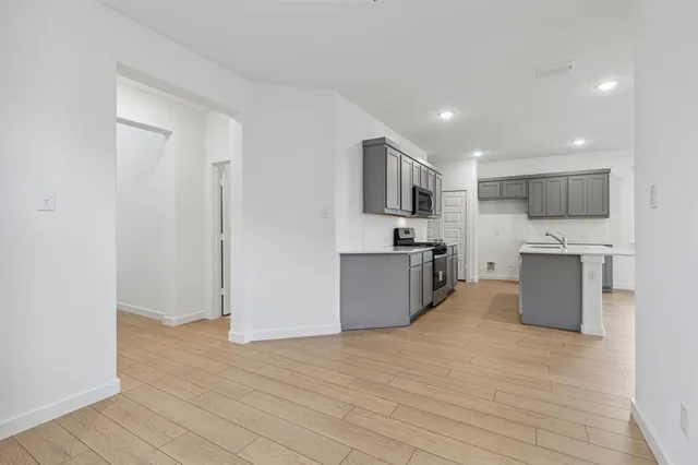 a view of kitchen with microwave oven a sink and cabinets