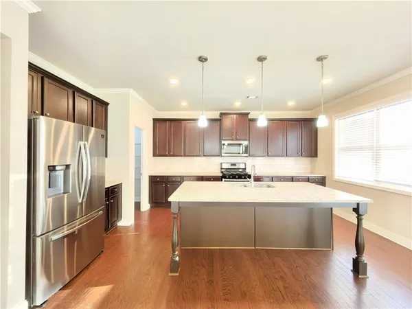 a large white kitchen with a refrigerator a sink dishwasher a stove and a refrigerator with wooden floor