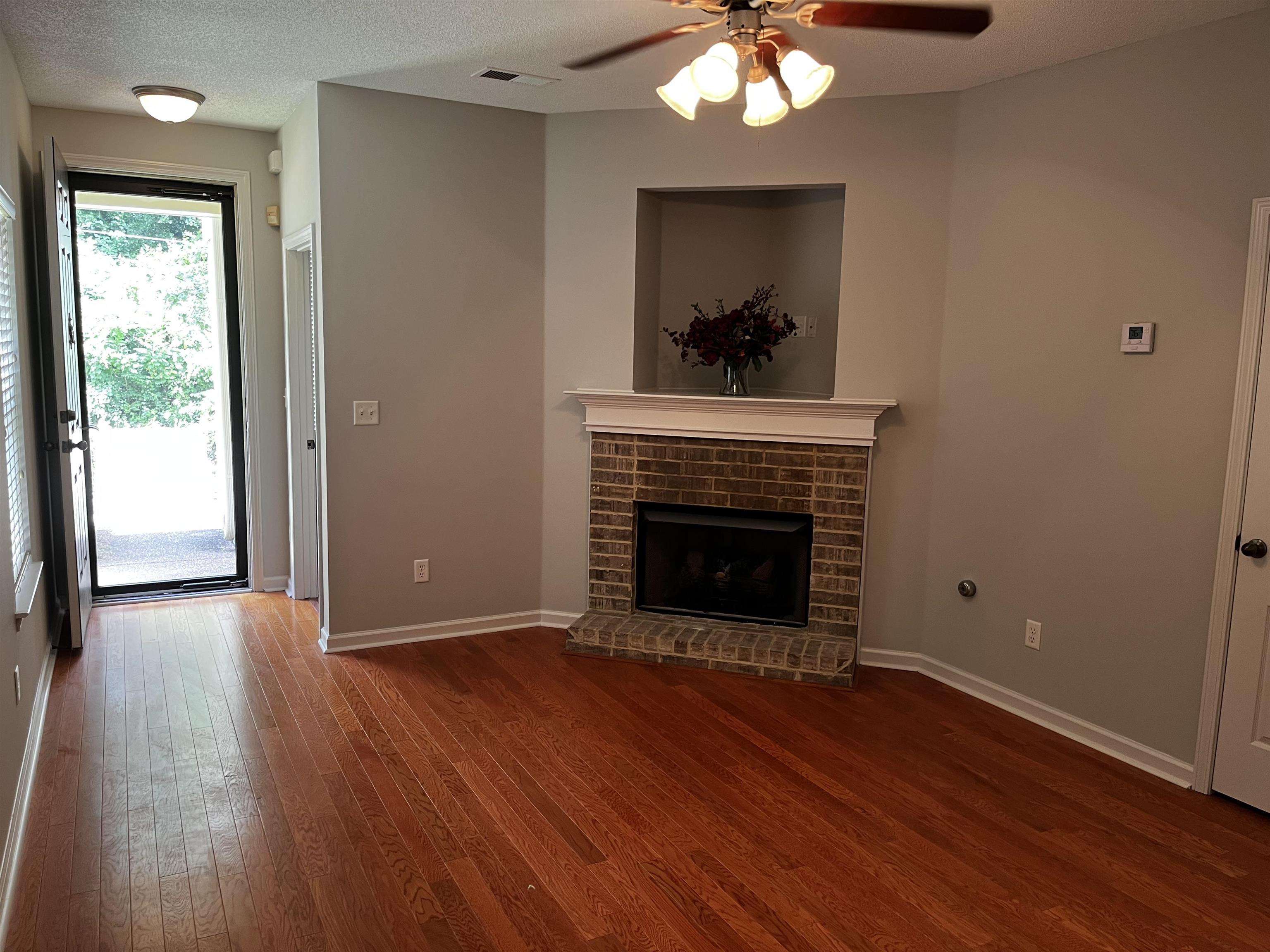 1182 Collierville Arlington Road Collierville, TN 38017 - Photo 3 of 34 a view of an empty room with wooden floor fireplace and a window