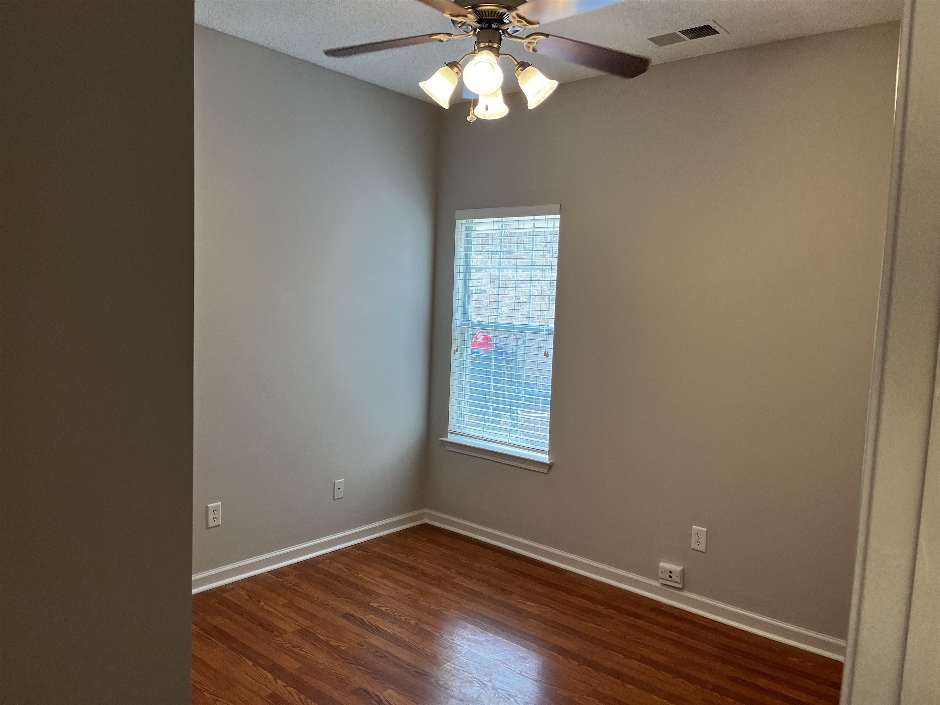 1182 Collierville Arlington Road Collierville, TN 38017 - Photo 7 of 34 an empty room with wooden floor chandelier fan and windows