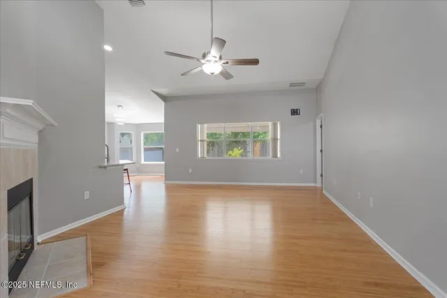 an empty room with wooden floor chandelier and windows