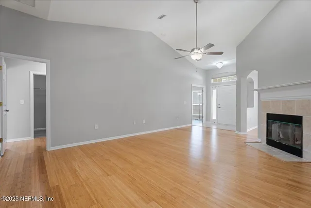 a view of an empty room with wooden floor fireplace and a window