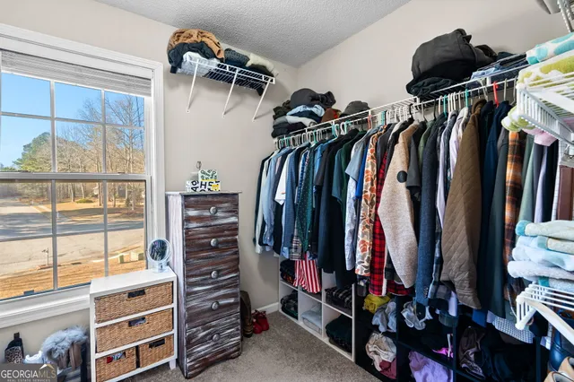 a view of walk in closet with clothes and shoes