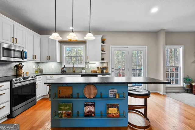 a kitchen with stainless steel appliances granite countertop a stove a sink dishwasher and cabinets with wooden floor