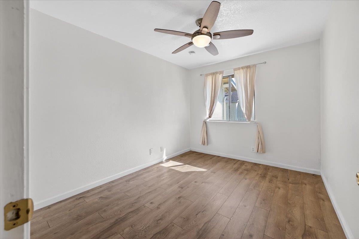 4875 North Backer Avenue, Unit 143 Fresno, CA 93726 - Photo 15 of 27 an empty room with wooden floor chandelier fan and windows