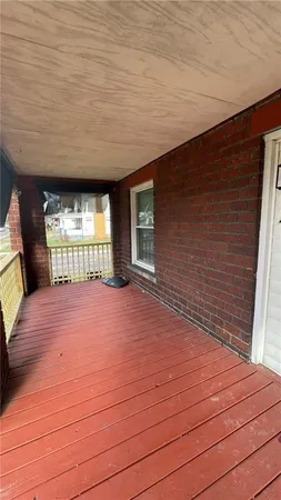 a view of an empty room with wooden floor and fan