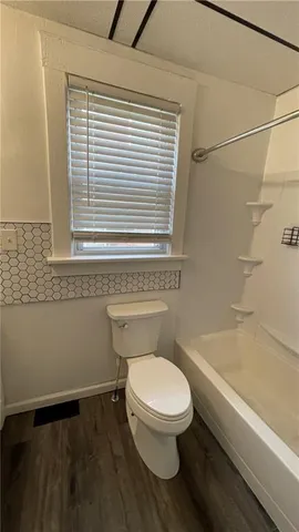 a white toilet sitting next to a bath tub