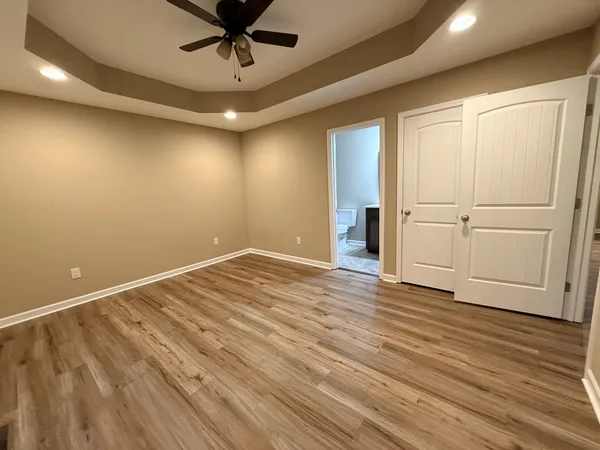 a view of empty room with wooden floor and fan
